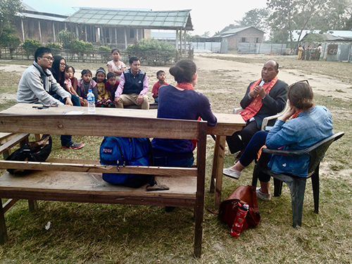 group of people sitting around a table outdoors in front of a building